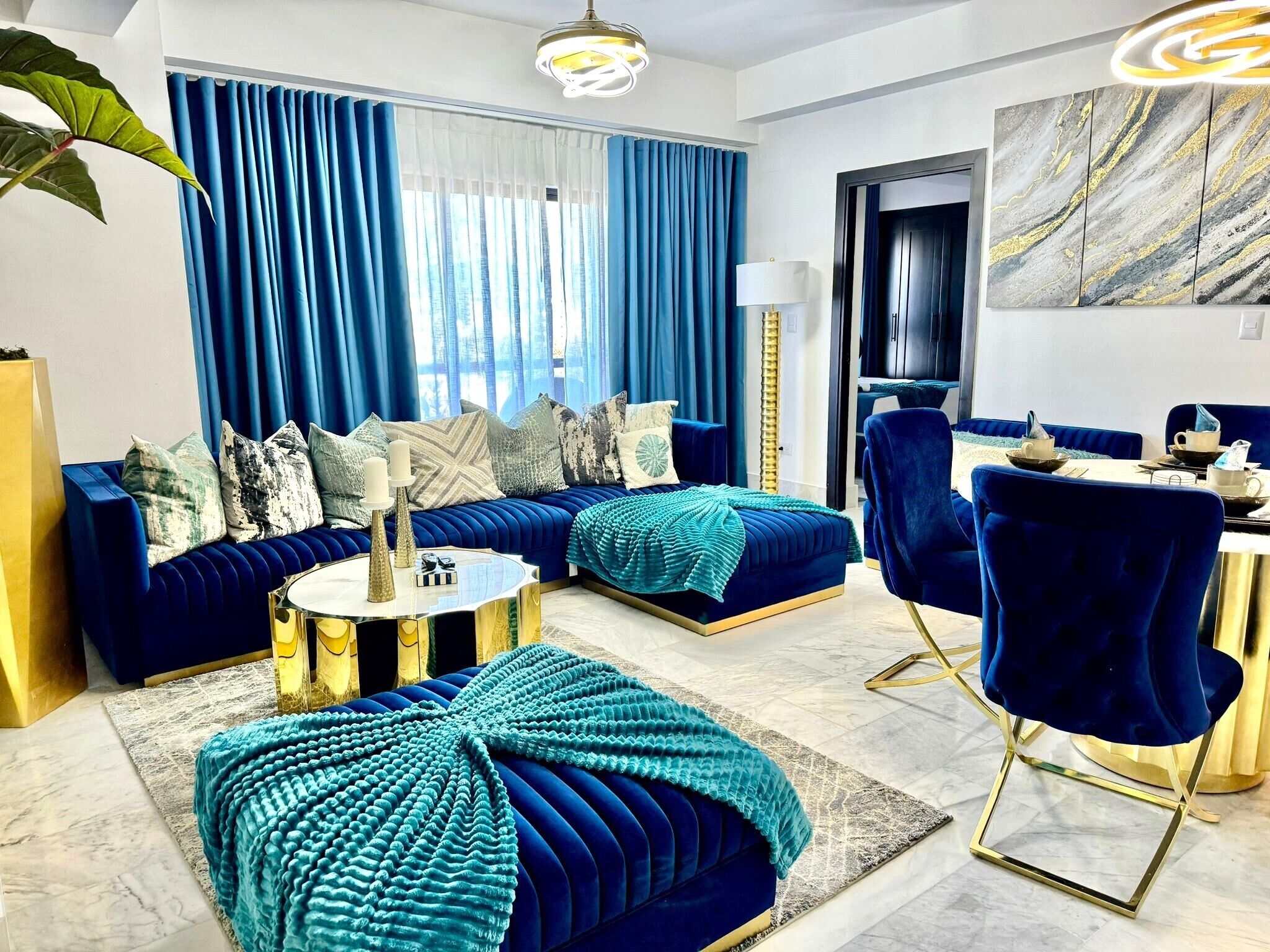 A modern living room with a sofa set, ottoman, and a dining area with chairs and a table.