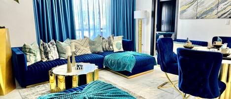 A modern living room with a sofa set, ottoman, and a dining area with chairs and a table.