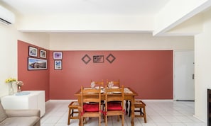 A dining area with a wooden table and chairs, a white sofa, and a white cabinet with a vase of flowers. - Apartment in the Center of Floripa Cpn0002 (Florianópolis)