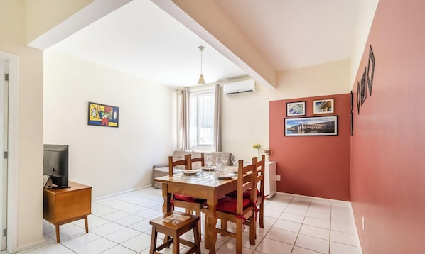 A dining area with a wooden table and chairs, a television on a stand, and artwork on the walls. - Apartment in the Center of Floripa Cpn0002 (Florianópolis)