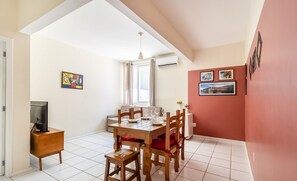 A dining area with a wooden table and chairs, a television on a stand, and artwork on the walls. - Apartment in the Center of Floripa Cpn0002 (Florianópolis)