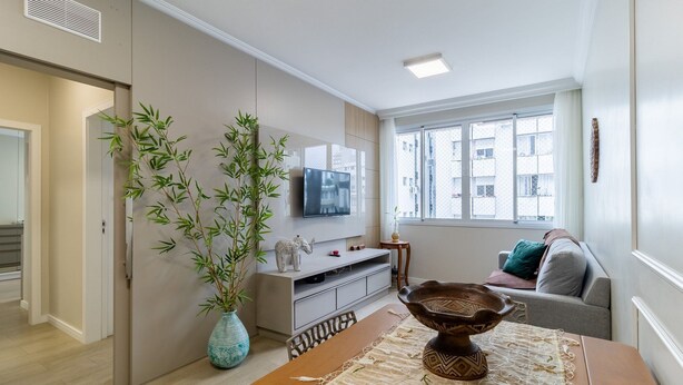 Una sala de estar moderna con televisor, sofá, mesa de comedor y un amplio ventanal.