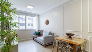 Una sala de estar con un sofá, una mesa de comedor y un ventanal grande.