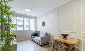 Ein Wohnzimmer mit einer Couch, einem Esstisch und einem großen Fenster.