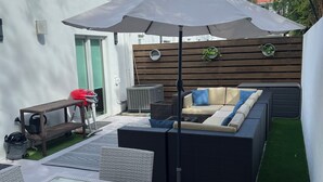 A patio area with a glass-top table, wicker chairs, a sofa, and a ceiling fan. - Tranquil Retreat – 2 Bedroom Las Olas (Fort Lauderdale)