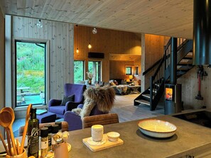 A cozy cabin interior with a fireplace, wooden walls, and a dining area.