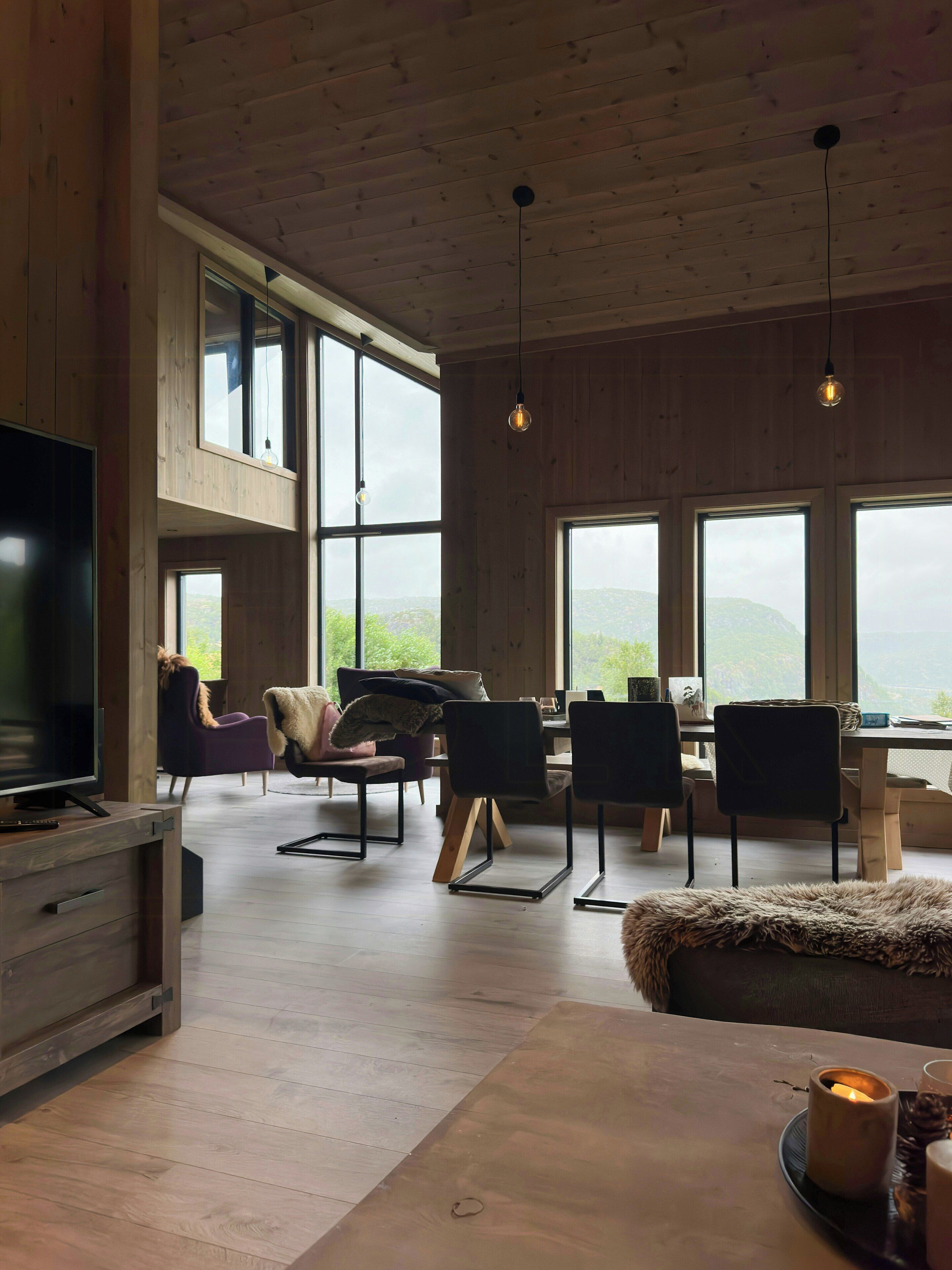 Amplia sala de estar con televisor, asientos y ventanas amplias que ofrecen vistas al exterior.
