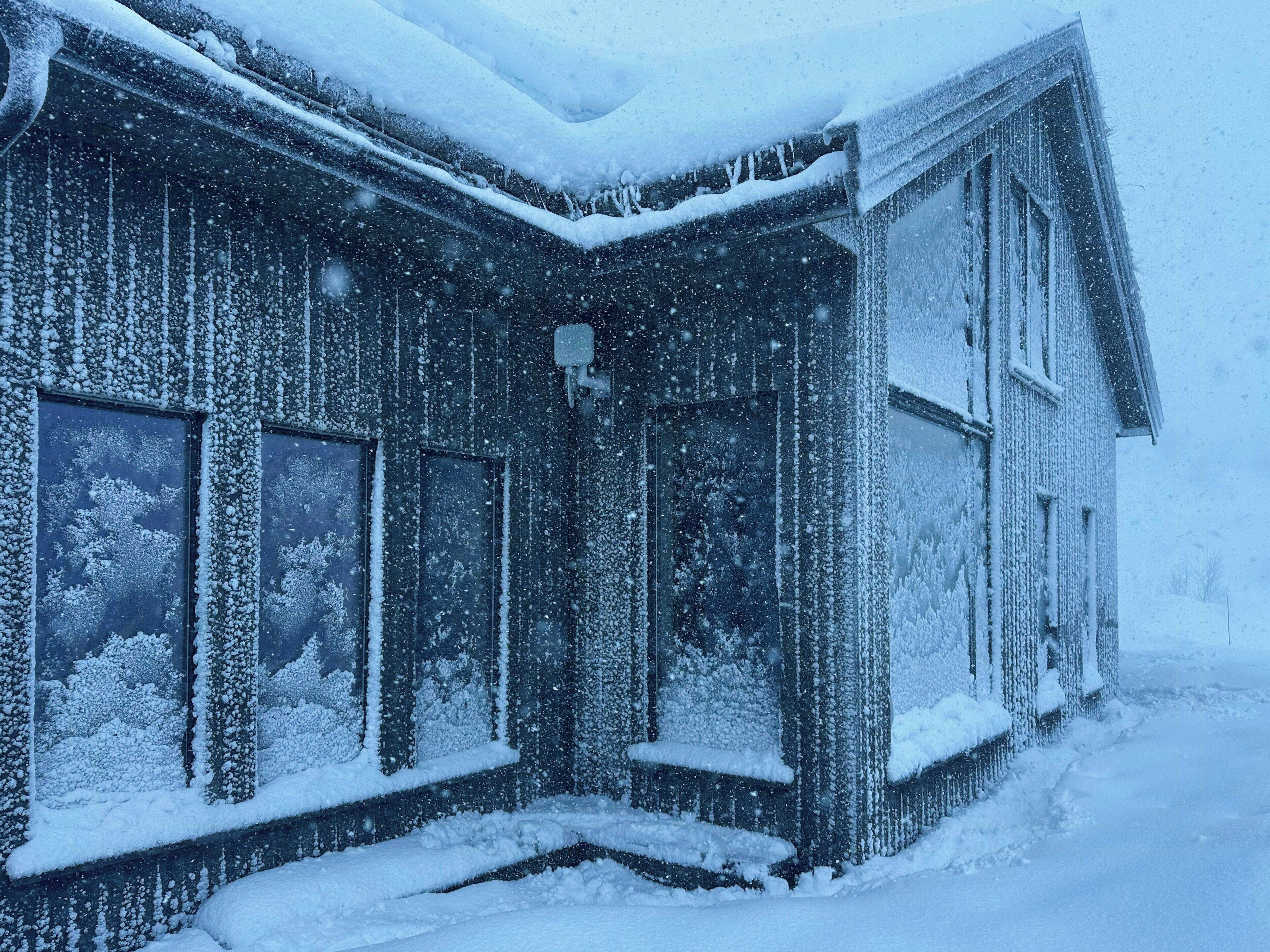 A snow-covered building with multiple windows and a snow-covered roof.