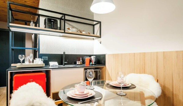 A compact kitchen with modern appliances, a dining area with a glass table, and a cozy seating arrangement.