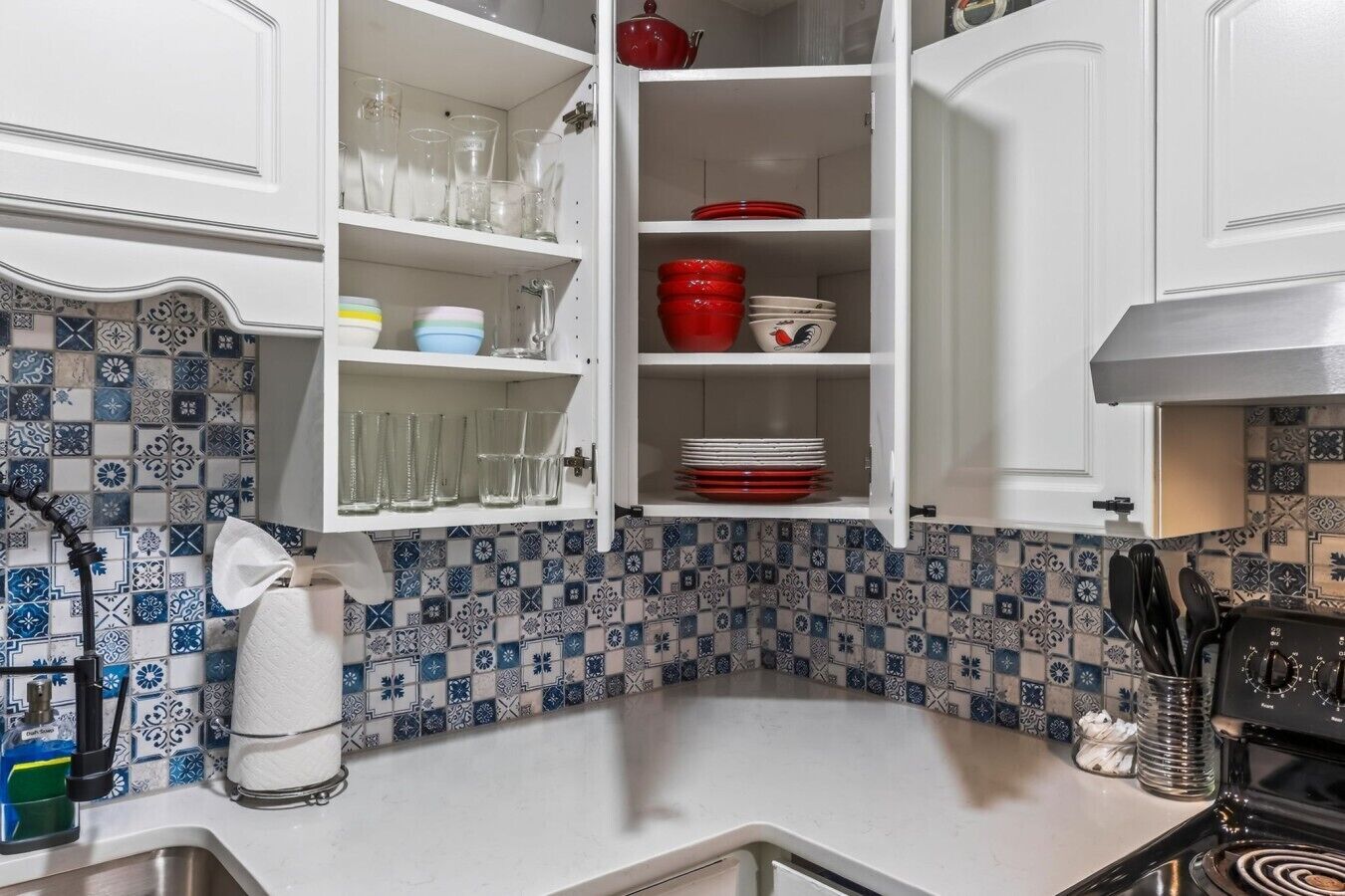 A kitchen with white cabinets, a tiled backsplash, and a stove.
