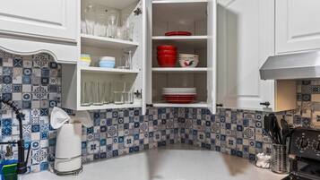 A kitchen with white cabinets, a tiled backsplash, and a stove.