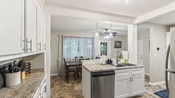 A modern kitchen with granite countertops, stainless steel appliances, and a dining area with a table and chairs.