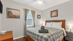 A bedroom with a bed, a nightstand, a desk, a ceiling fan, and two framed pictures on the walls. - 3 bdrm, 7 Minutes from downtown (Kansas City)