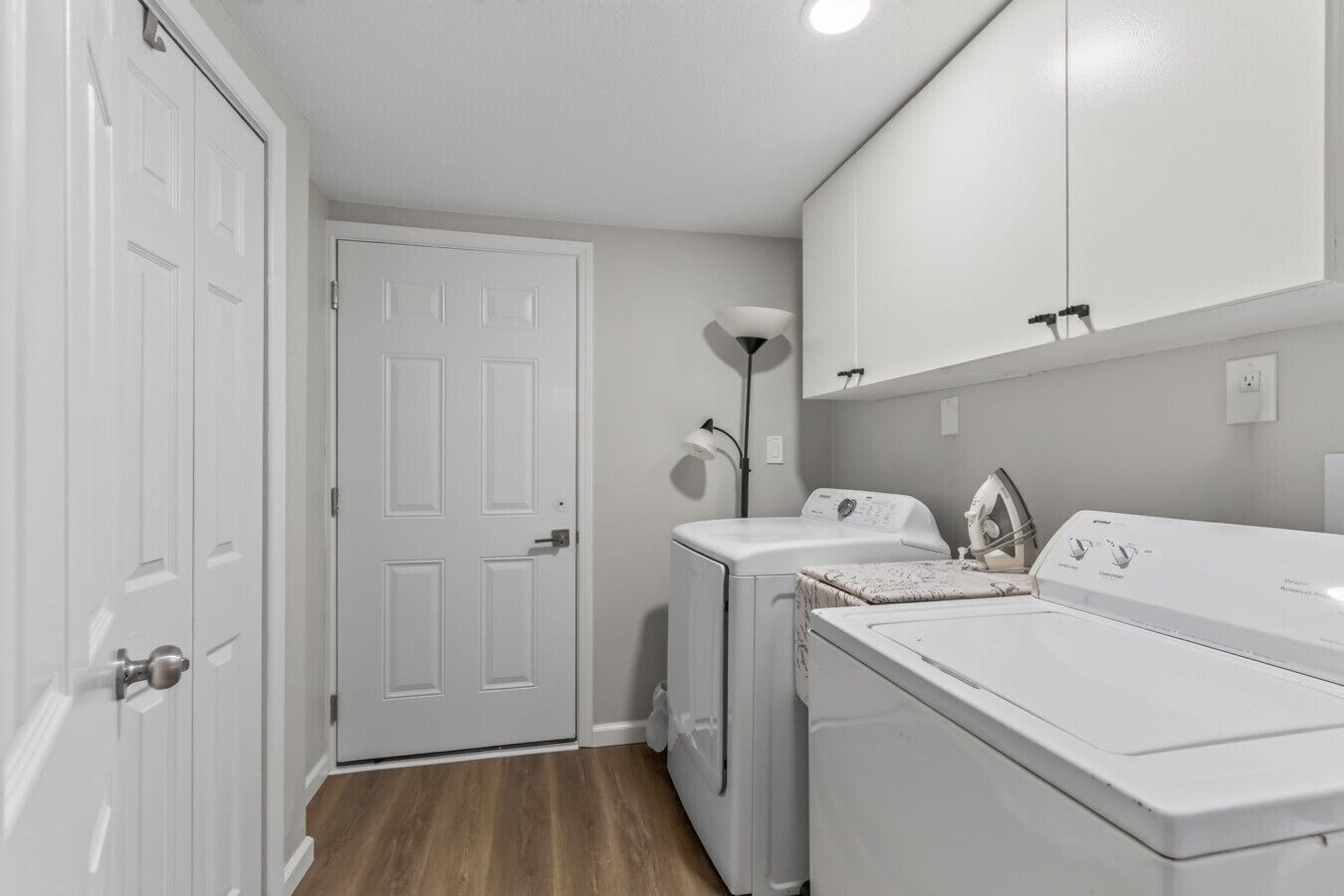 A laundry room with a washing machine, dryer, and a door.