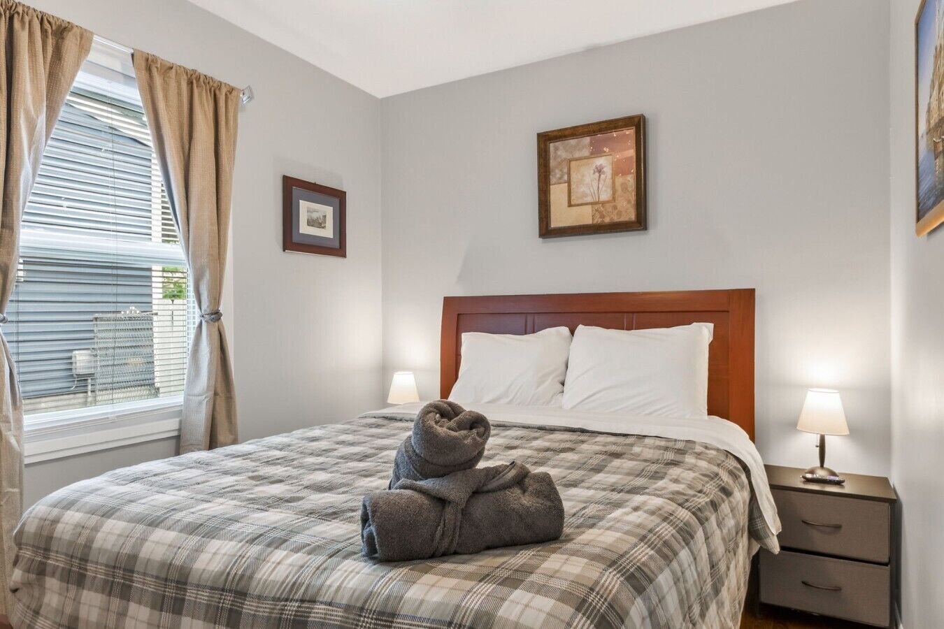 Ein Hotelzimmer mit Bett, Nachttisch, Lampe und einem Vorhangfenster.