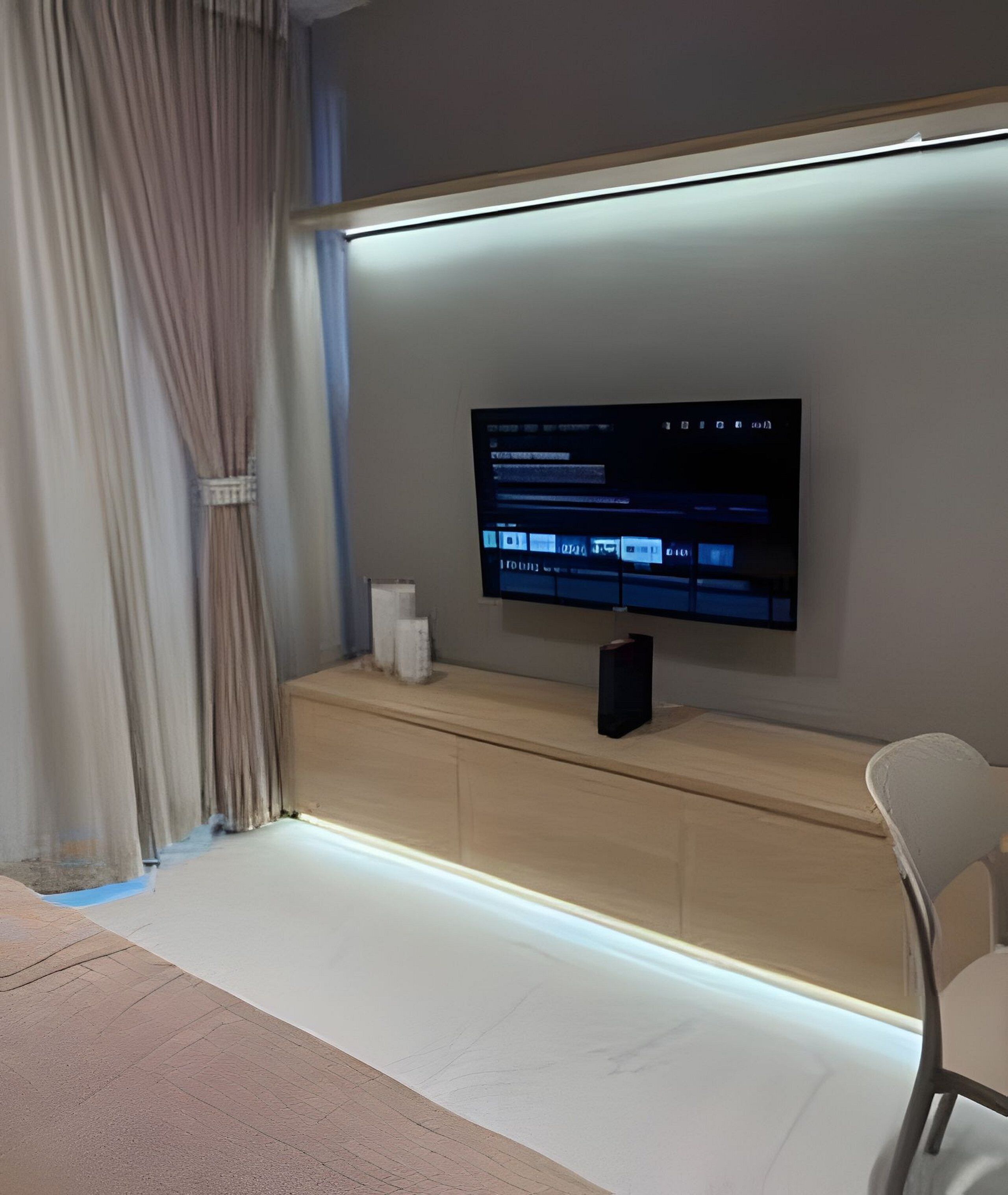 Un soggiorno moderno con una TV a schermo piatto montata sulla parete, un tavolino consolle in legno e una poltrona.