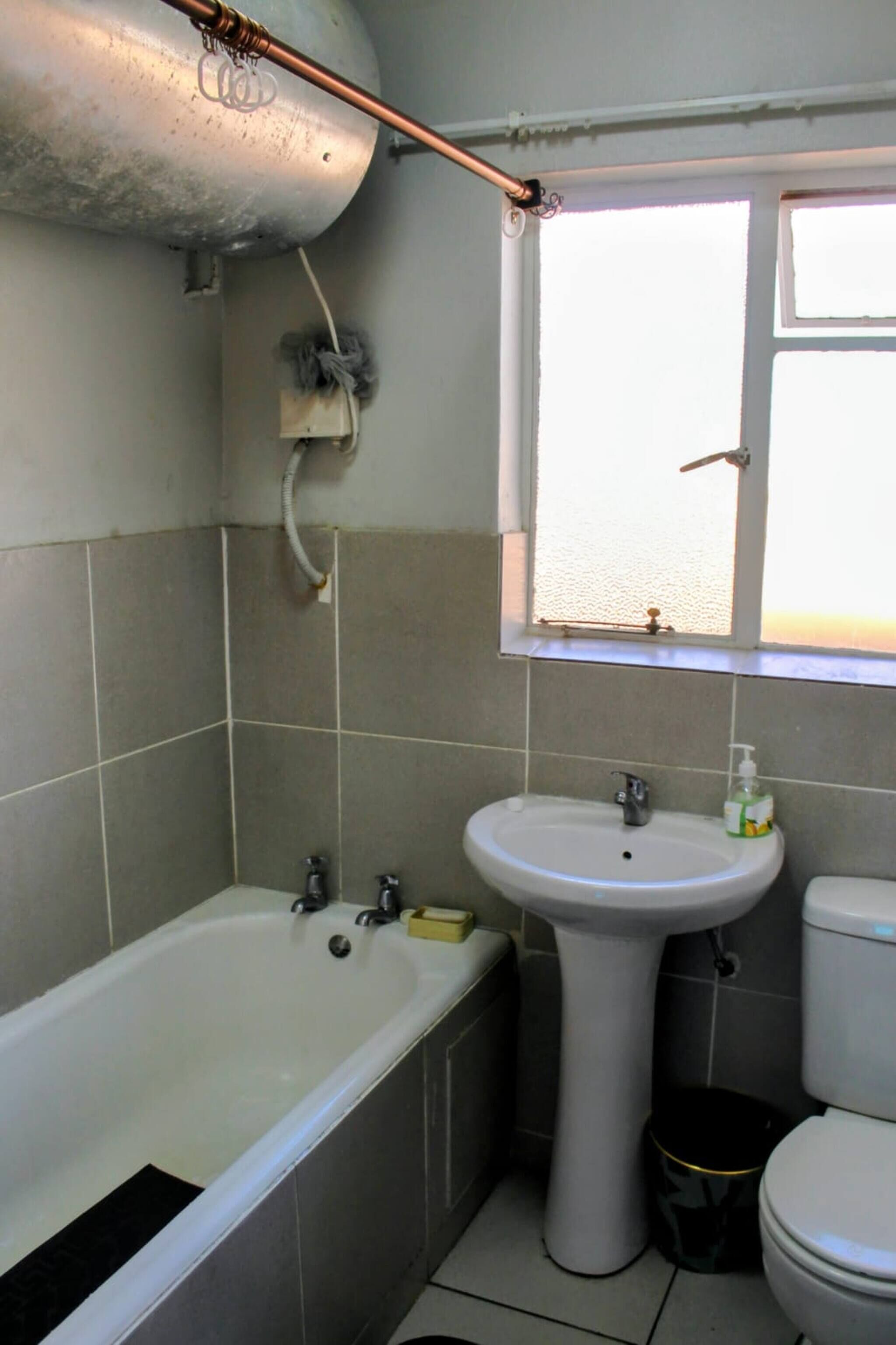 Un baño con bañera, lavamanos, inodoro y ventana.