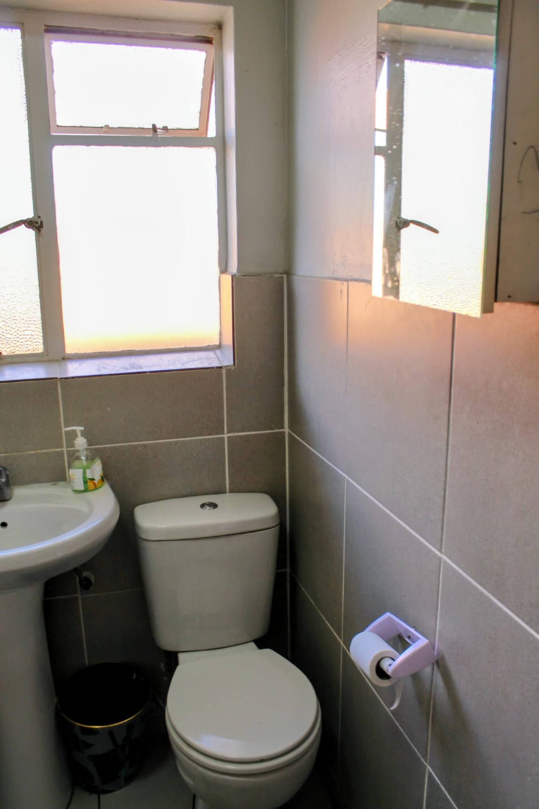 Un baño pequeño con inodoro, lavamanos y ventana.