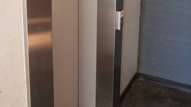 Un ascensor estrecho con paredes y puerta metálicas.