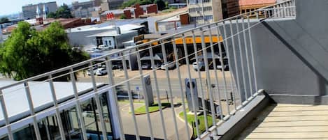 Un balcon donnant sur un parking et des immeubles.