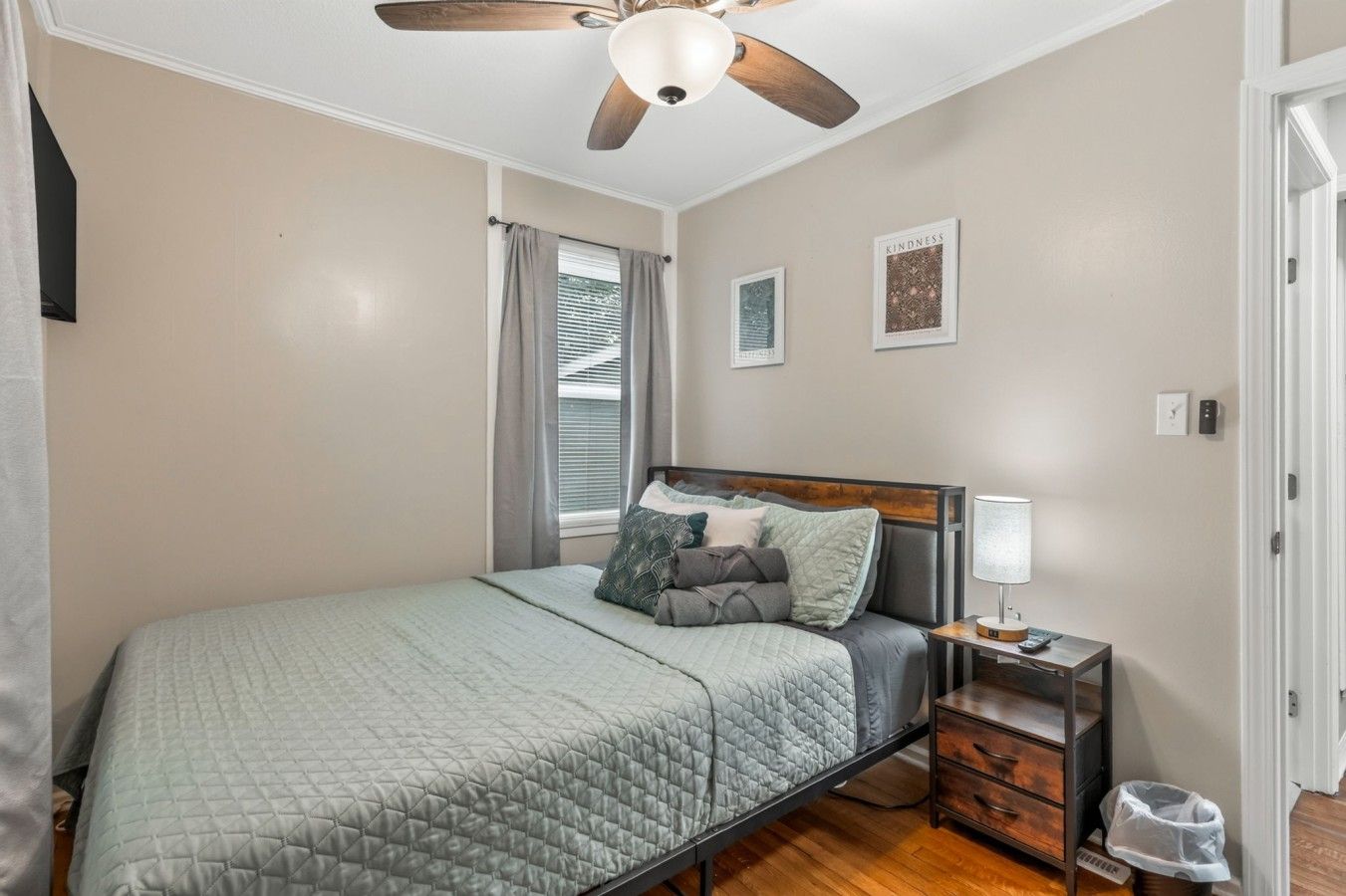 A bedroom with a bed, a nightstand, a lamp, and a ceiling fan.