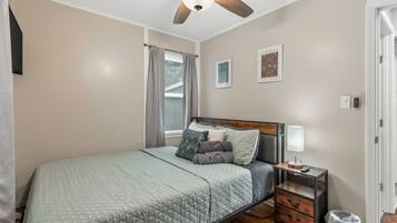 A bedroom with a bed, a nightstand, a lamp, and a ceiling fan.