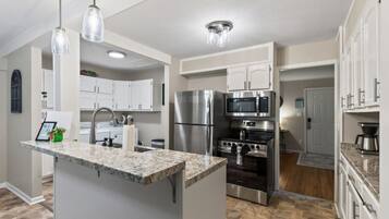 A modern kitchen with granite countertops, stainless steel appliances, and pendant lighting.