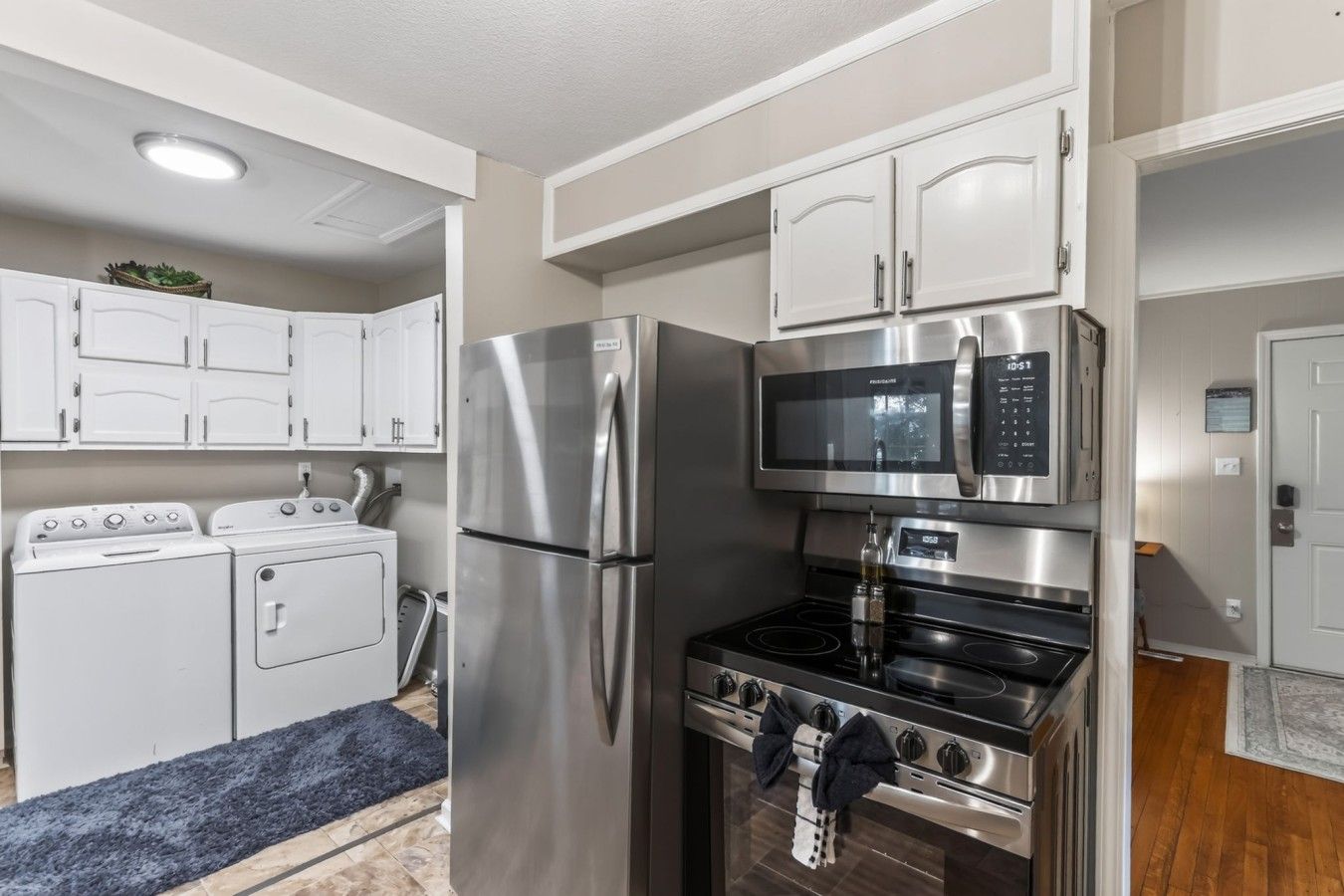A compact kitchen with stainless steel appliances, including a refrigerator, microwave, and stove, and a washing machine.