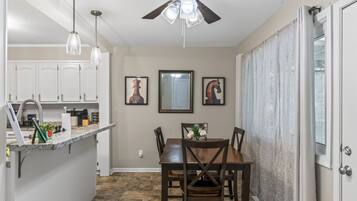 Une cuisine de taille réduite avec un coin repas, un ventilateur de plafond et une table à manger avec des chaises.