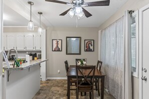 Una cocina compacta con comedor, ventilador de techo y mesa con sillas.