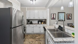 A modern kitchen with stainless steel appliances, white cabinetry, a granite countertop, and a stainless steel sink. - 2Bdrm - 7 Minutes To Downtown (Kansas City)