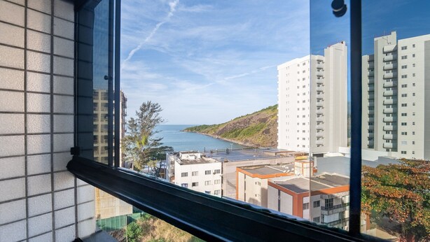 Vista desde una ventana sobre una zona costera con edificios y cielo despejado.
