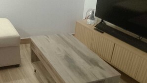 Ett rum med ett soffbord i trä, en tv på ett träställ och ett golv i en ljus färg.