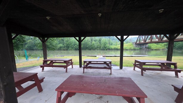 An outdoor pavilion with picnic tables and a view of a lake.