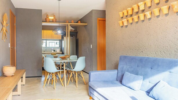 A modern living room with a blue sofa, a dining area with a table and chairs, and a kitchen in the background. - Nice Apart Near Patacho Beach Cvpa103 (Porto de Pedras)