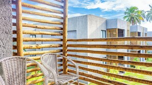A balcony with a wooden slatted railing, wicker chairs, and a view of modern buildings and palm trees. - Nice Apart Near Patacho Beach Cvpa103 (Porto de Pedras)