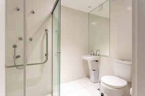 A modern bathroom with a glass shower enclosure, a white toilet, and a sink with a mirror above it. - Studio w/ Balcony 450m From Allianz Parque Dio0507 (São Paulo)