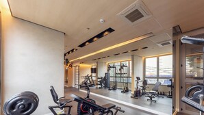 Ein Fitnessstudio mit Trainingsgeräten, Spiegeln und großen Fenstern.