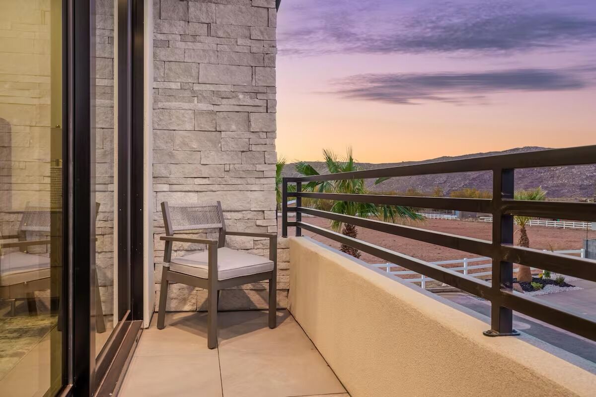 A balcony with a stone wall, a chair, and a view of a desert landscape.