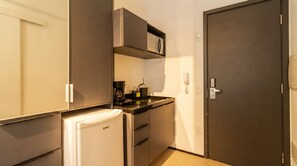 A compact kitchen with a refrigerator, a microwave, a coffee maker, and a sink. - Studio c Academia 350m do Nubank Parque Perdizes (São Paulo)