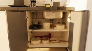 Uma cozinha com pia embutida, cafeteira e diversos utensílios e recipientes de cozinha.