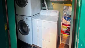 A laundry room with two stacked washing machines and a shelf with folded towels and laundry supplies. - 2 waterfront cabins, Jack & Jill bath, steps to Lake, restaurant and bar (Troy)