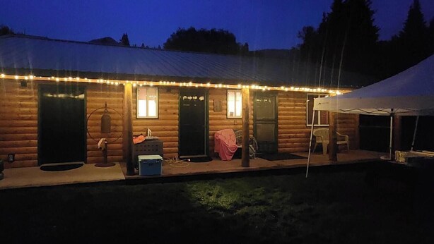 A log cabin with a covered porch, a small outdoor seating area, and a tent. - 2 waterfront cabins, Jack & Jill bath, steps to Lake, restaurant and bar (Troy)