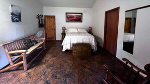 A bedroom with a bed, wooden bench, and a fan. - 2 waterfront cabins, Jack & Jill bath, steps to Lake, restaurant and bar (Troy)