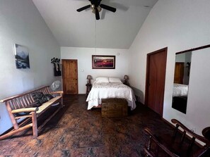 Ein Schlafzimmer mit einem Bett, einer Holzbank und einem Ventilator.