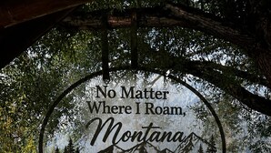 A circular sign with text and a mountain landscape, located in a park with a bench and a picnic table. - 2 waterfront cabins, Jack & Jill bath, steps to Lake, restaurant and bar (Troy)