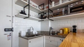Et moderne køkken med hvide skabe, granitbordplader og indbyggede apparater, herunder kaffemaskine, elkedel og brødrister.
