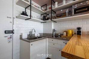 A modern kitchen with white cabinets, granite countertops, and built-in appliances including a coffee maker, kettle, and toaster. - Studio With Heated Pool, at DF Plaza Dpa210 (Águas Claras)