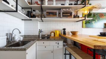 Cozinha moderna com armários brancos, bancada de granito, forno embutido e mesa de jantar de madeira.