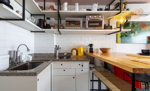 A modern kitchen with white cabinets, a granite countertop, a built-in oven, and a wooden dining table. - Studio With Heated Pool, at DF Plaza Dpa210 (Águas Claras)